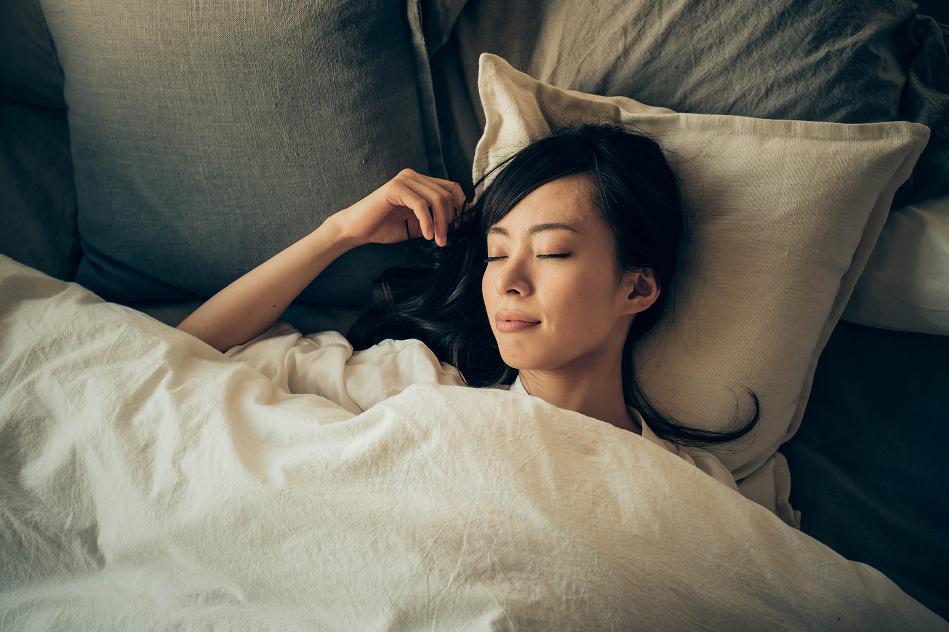 Une femme allongée dans son lit qui profite d'une meilleure nuit de sommeil grâce aux conseils du Dre Colleen Carney, spécialiste du sommeil chez LifeSpeak.