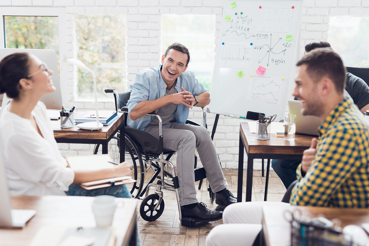 Plusieurs employés, dont un en fauteuil roulant, collaborent dans un lieu de travail où les capacités sont diverses.