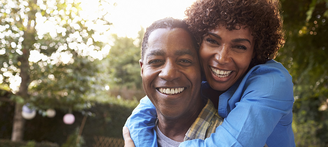 older man and older woman hugging each other and smiling