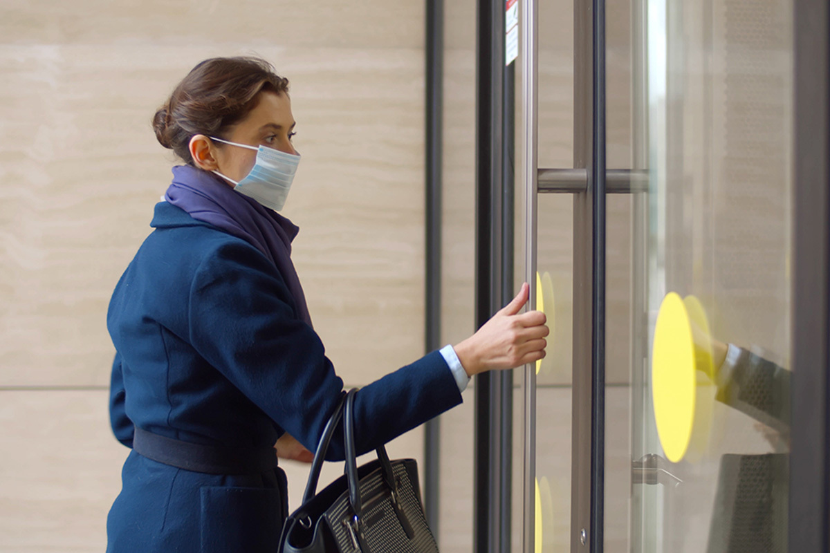 A woman wearing a mask enters the physical office for the first time since the pandemic began.