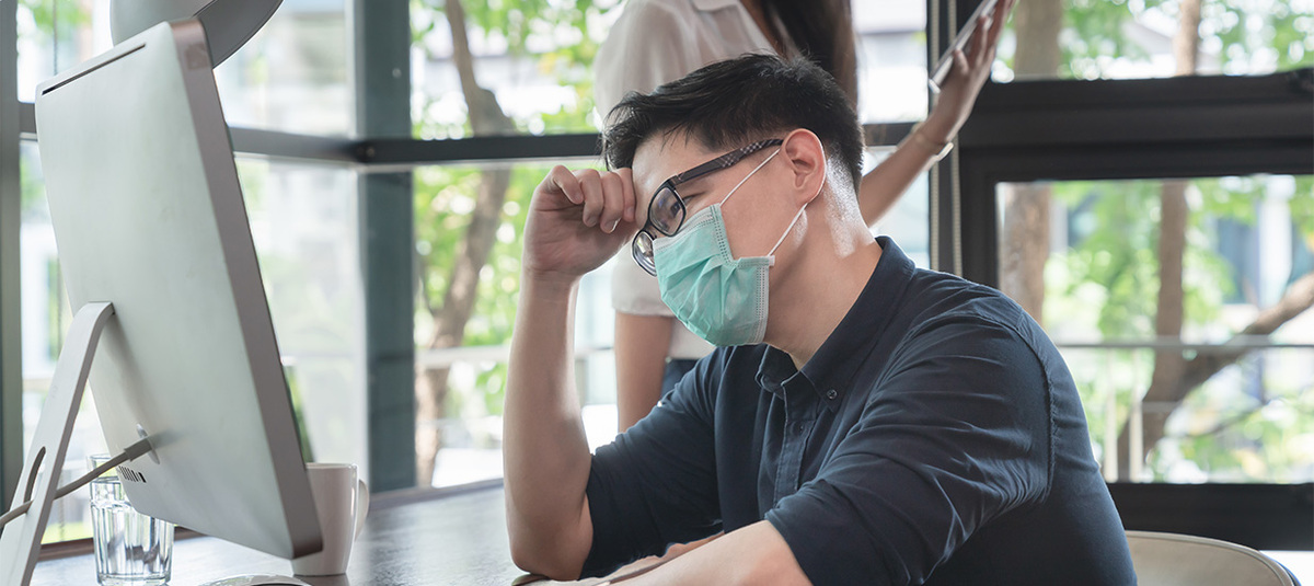 Adult Asian male wearing a surgical mask looks tired