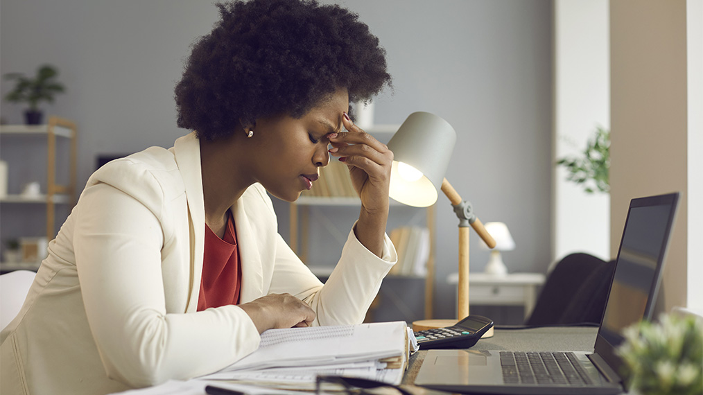Black woman looking tired at work desk