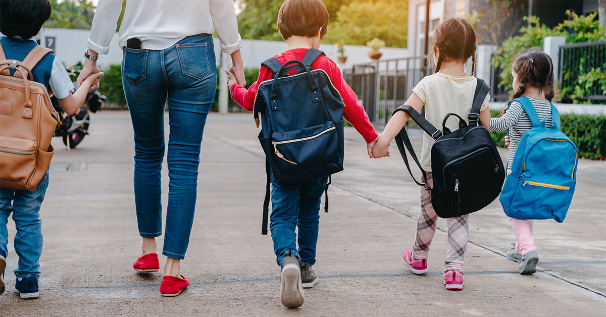 Image of a woman walking 4 young children to school