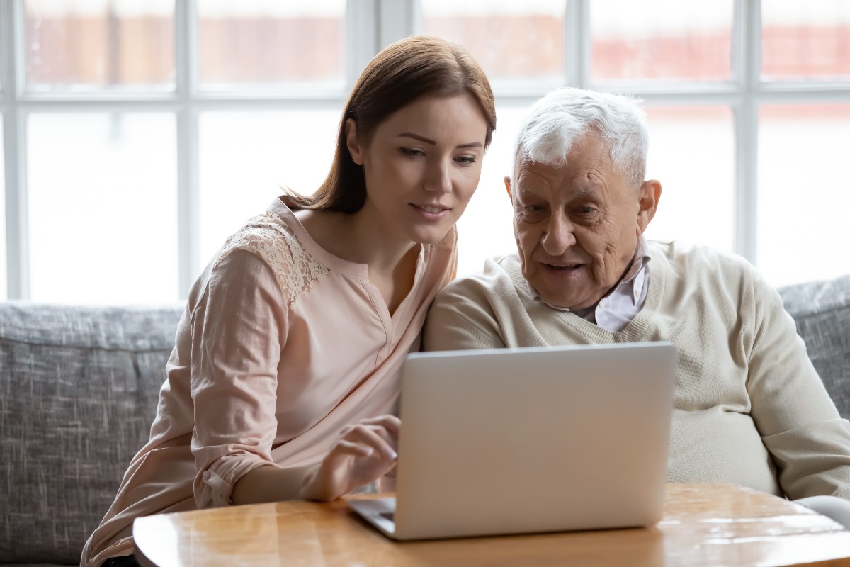 A caregiver and her father build better habits by watching education videos on a laptop.