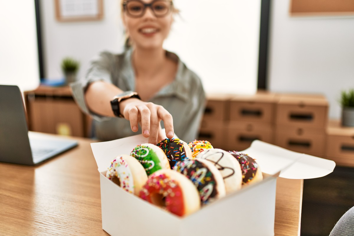 An employee reaches for a donut during her work day.