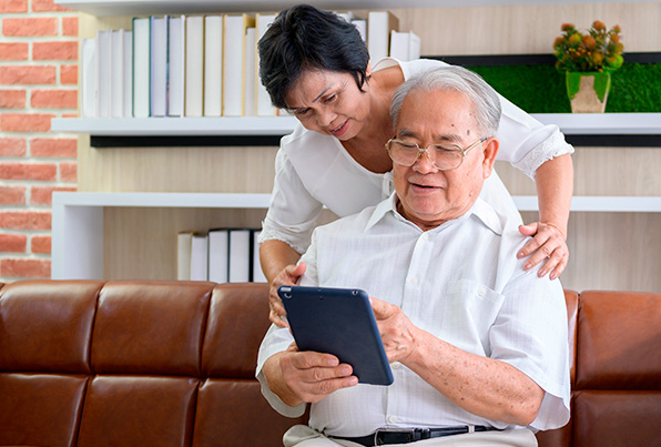 elderly man and woman looking at tablet together