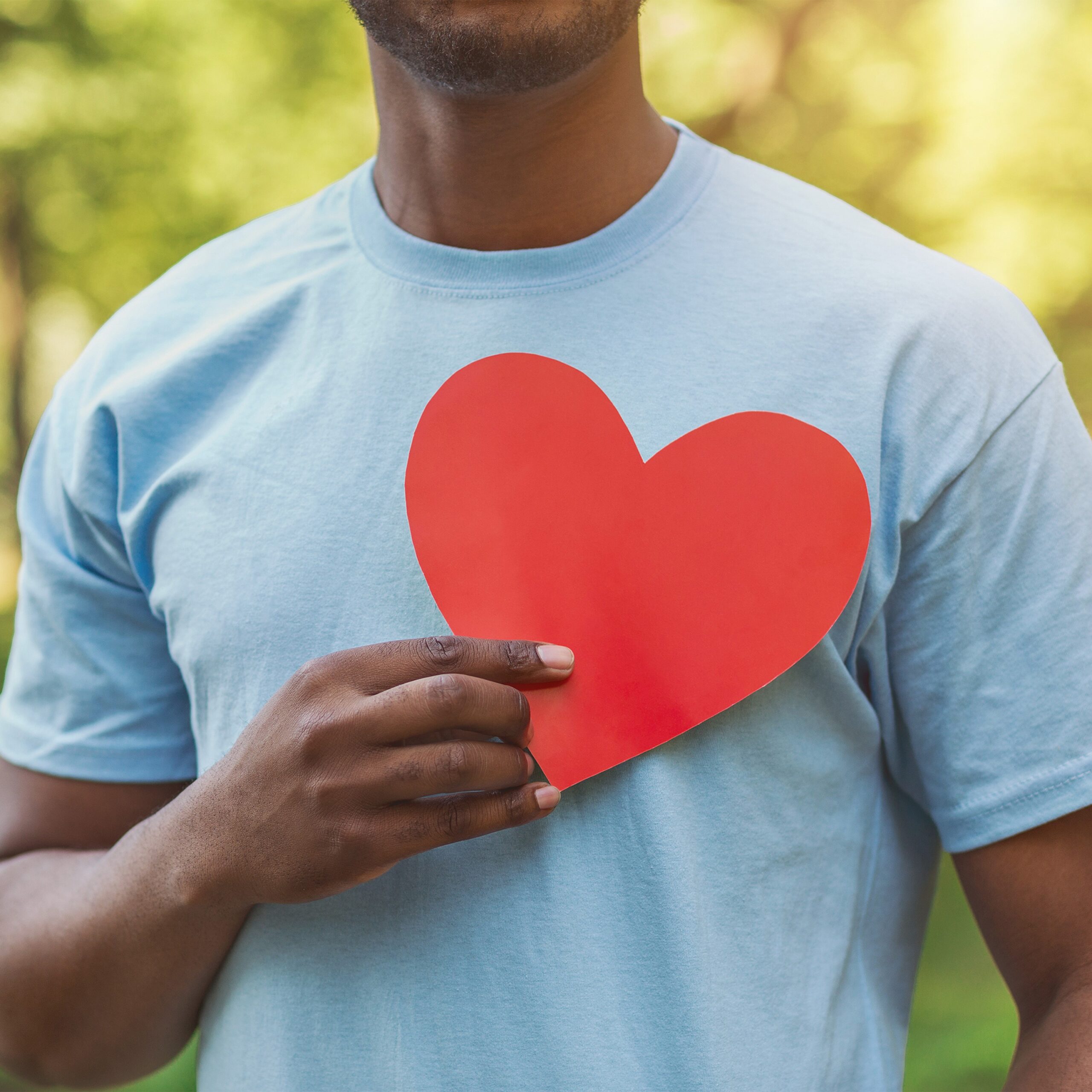 man holding red paper heart over his chest