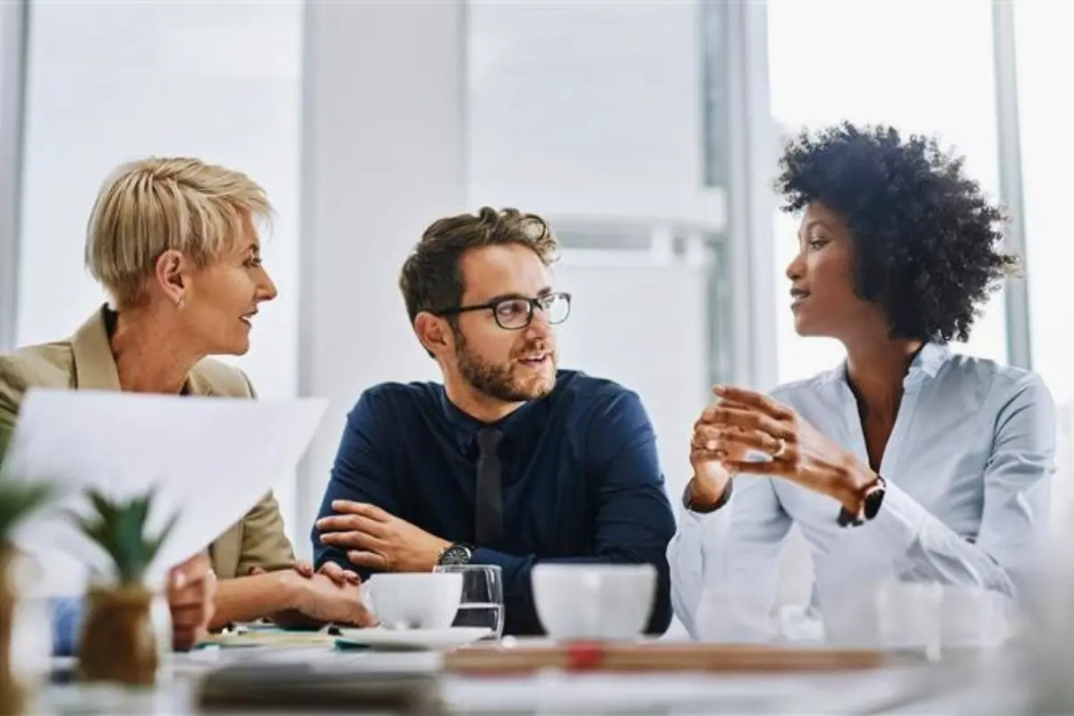 Three professionals in discussion around a meeting table, reflecting a collaborative workplace setting focused on employee wellbeing and substance use support