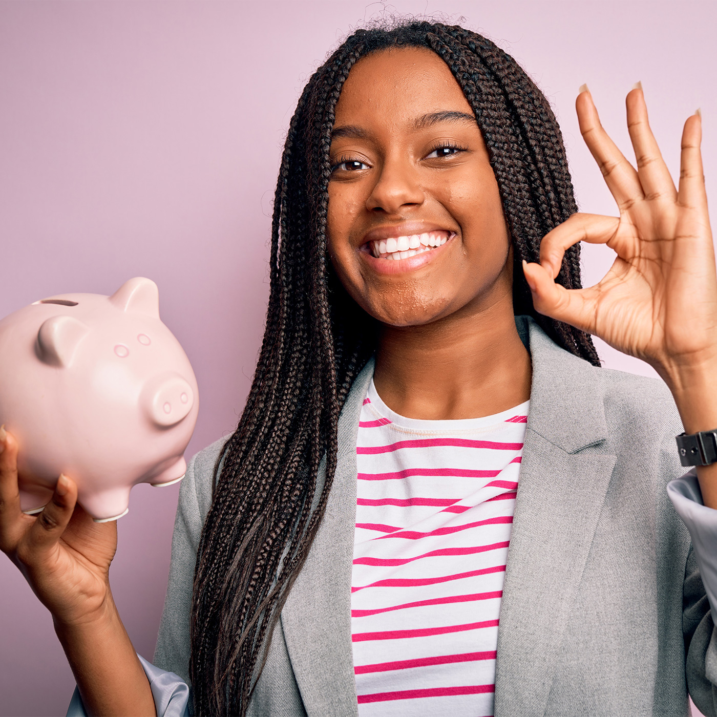 Teenage girl smiling while holding piggy bank