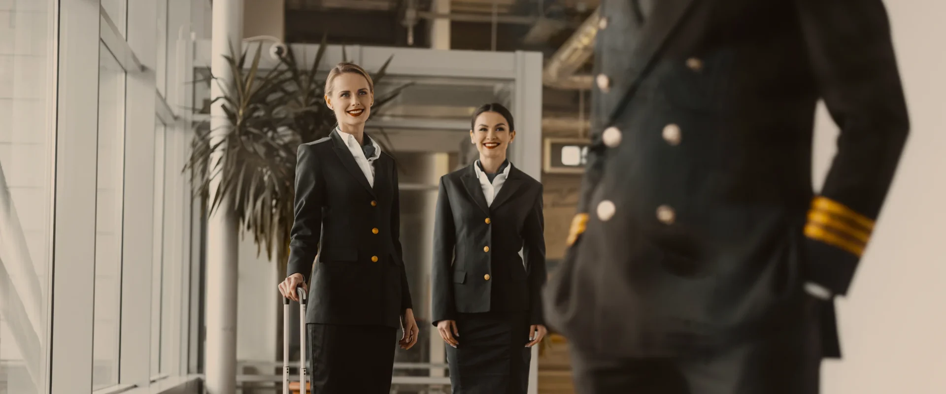 Airline crew greeting captain, smiling in uniform at an airport terminal.