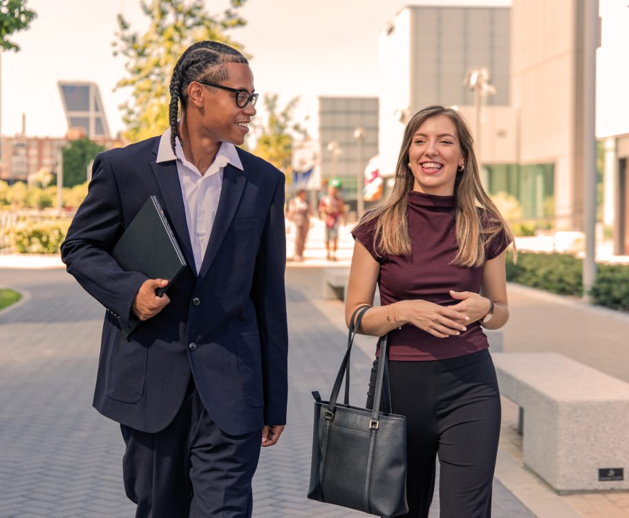 Two professionals walking and talking in a modern city setting.