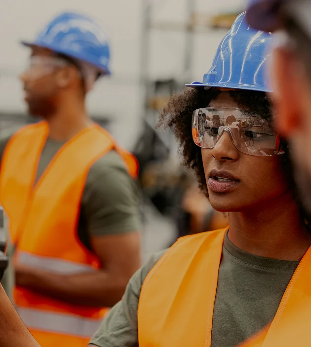Construction workers wearing safety vests and helmets on site.