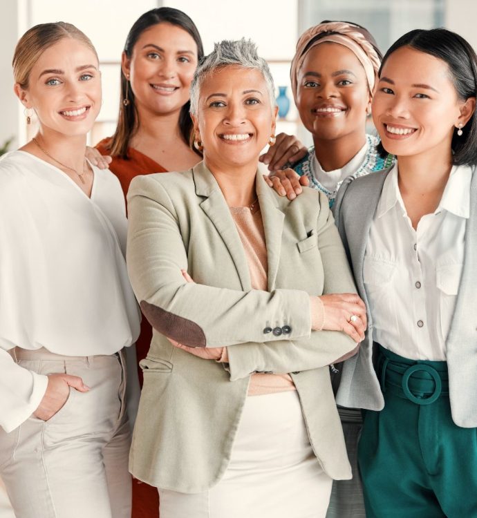 Diverse group of professional women smiling confidently in a bright office setting.