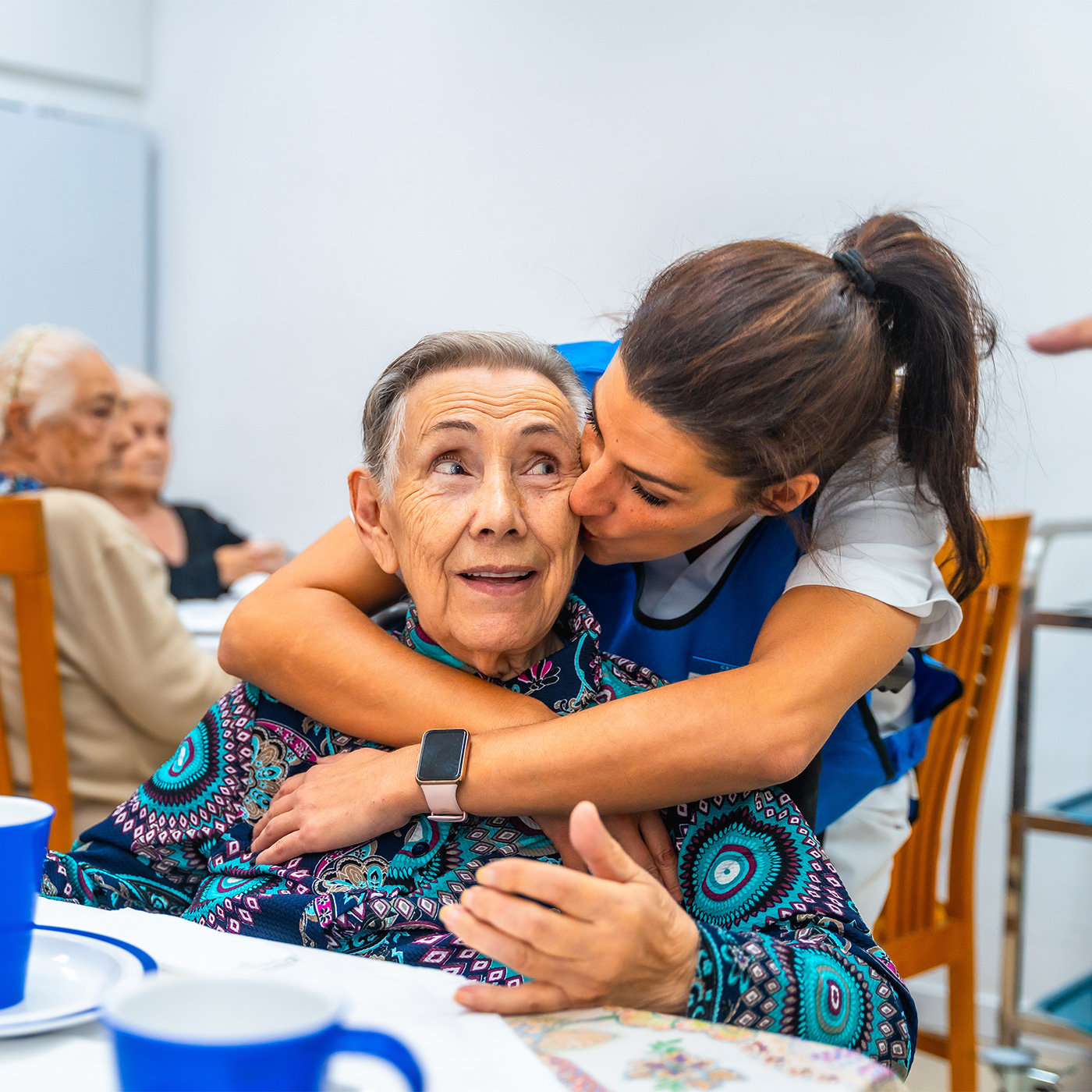 older woman being hugged by caregiver