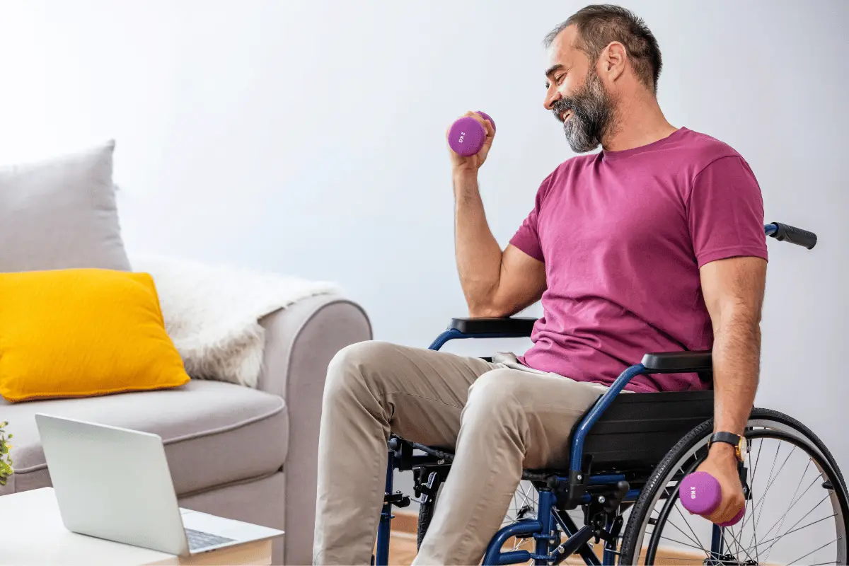 Man in wheelchair performing adaptive strength training with dumbbells during online fitness session at home, part of inclusive workplace wellness program.