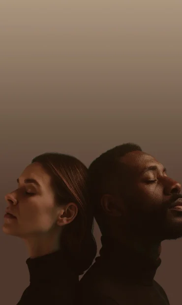 Two people back-to-back with eyes closed, calm expression and neutral background.