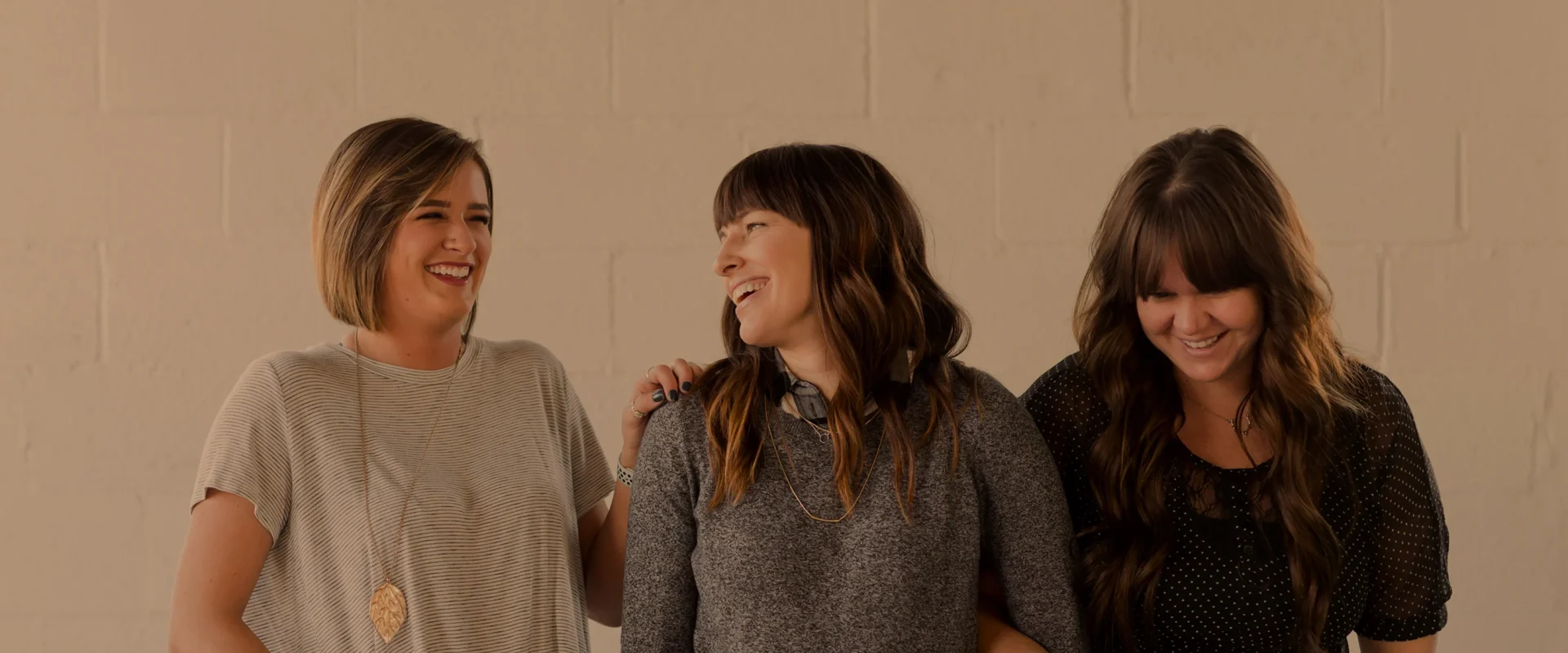 Three women laughing together in a friendly moment.