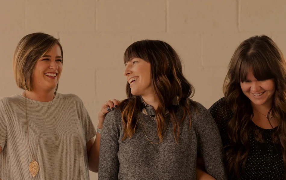 Three women laughing together in a friendly moment.