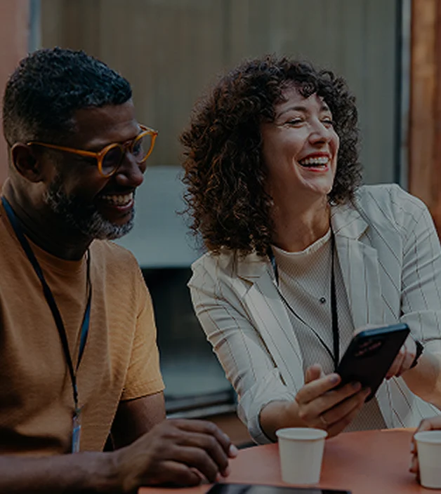 Smiling colleagues using smartphone at a coffee break.
