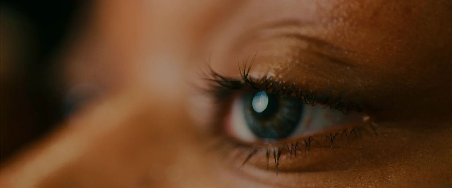 Close-up of a person's eye with long eyelashes.