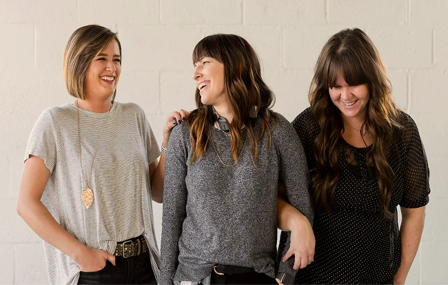 Three friends laughing and enjoying each other's company in a casual setting.