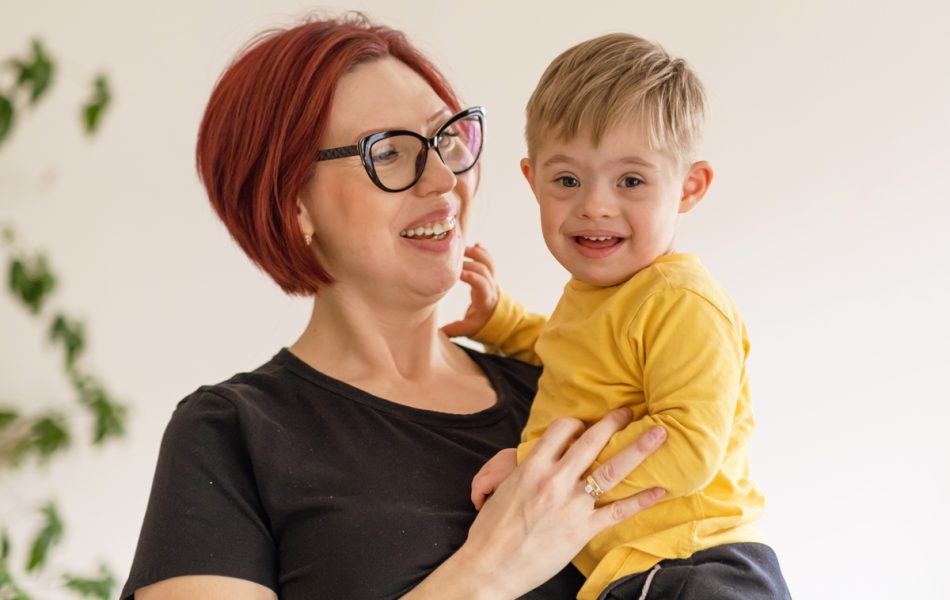 Smiling woman holding a happy child in yellow, creating joyful family moments indoors.