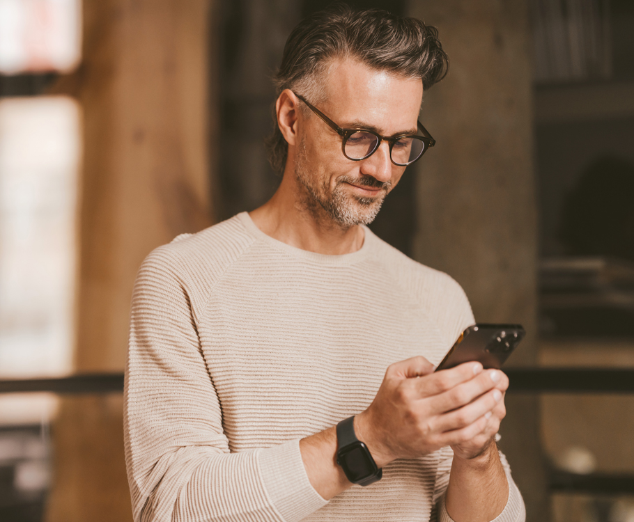 Man in casual sweater using smartphone indoors.