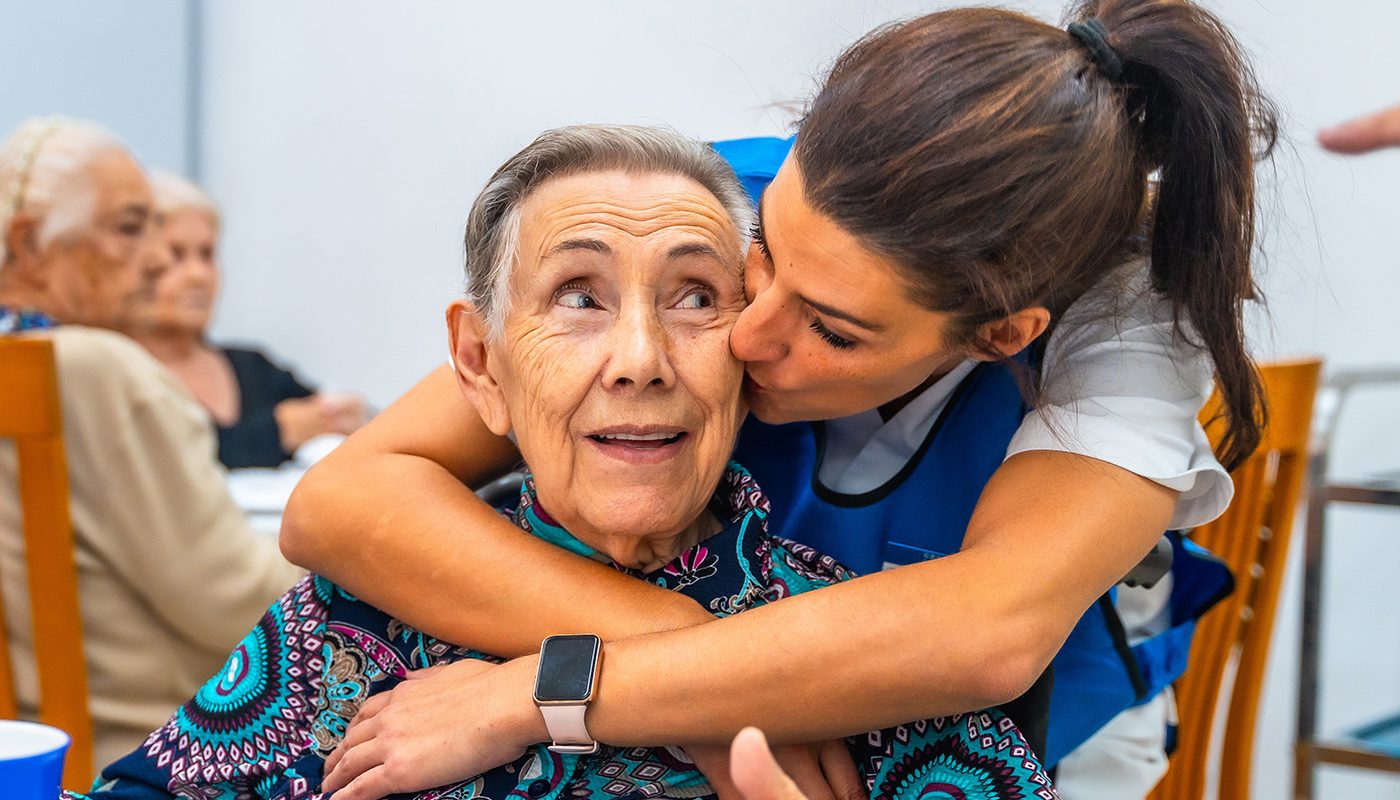 older woman being hugged by caregiver