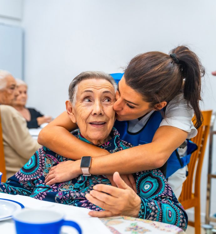 older woman being hugged by caregiver