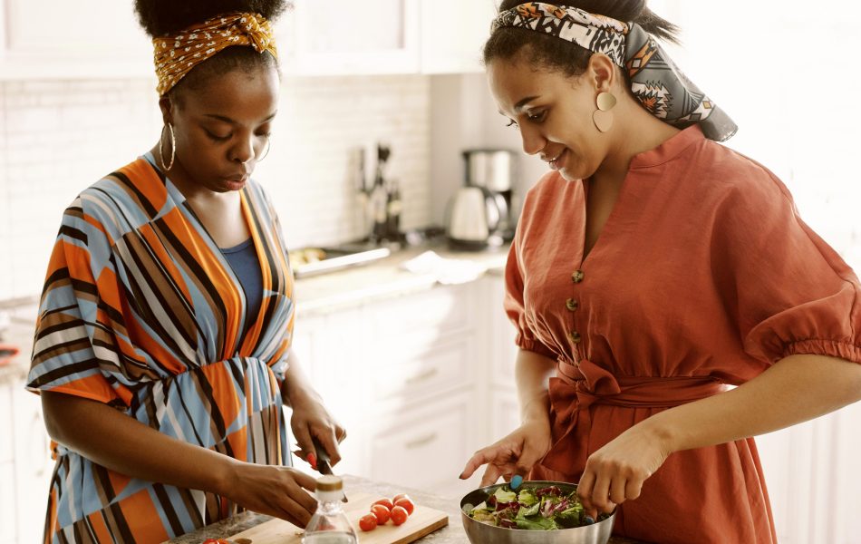 Two women preparing a fresh salad together in a bright kitchen.