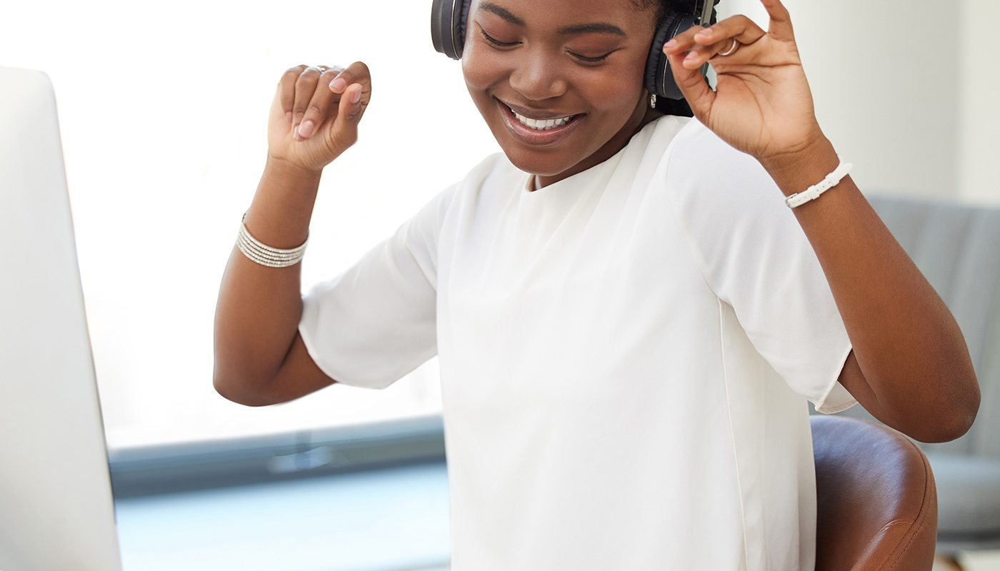 happy woman wearing headphones at her desk