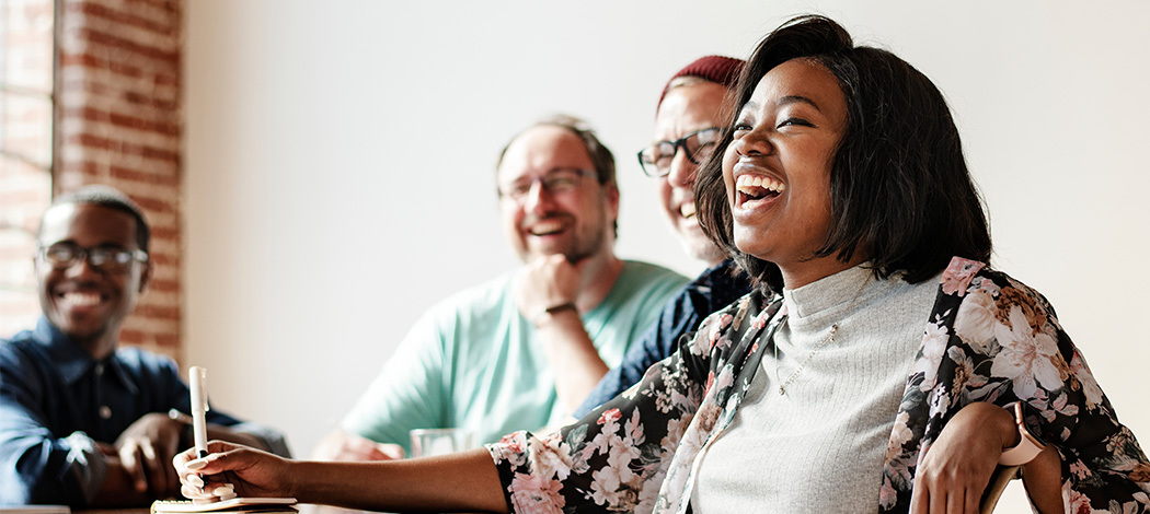 Smiling diverse group sharing a joyful moment at a casual meeting in a bright room.
