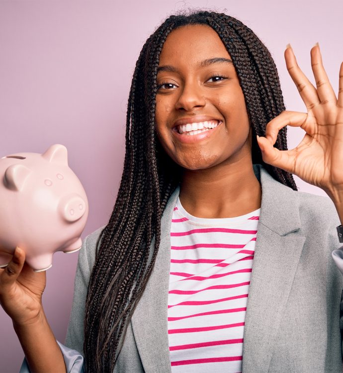 Teenage girl smiling while holding piggy bank