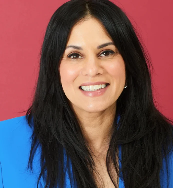 Smiling woman in a blue blazer against a red background.
