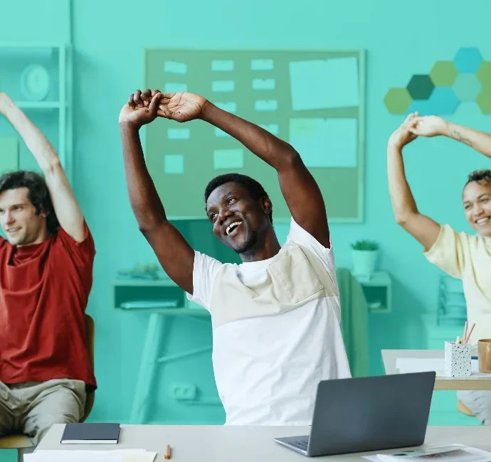 Office workers doing stretches at desk, promoting workplace wellness and productivity.