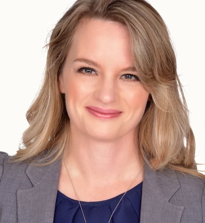 Smiling blonde woman in a gray blazer, professional studio headshot on white background