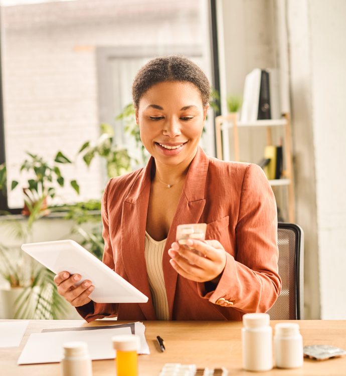 Woman using tablet and reviewing supplements at a desk.