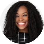 Smiling woman with curly hair and checkered top, portrait on white background.