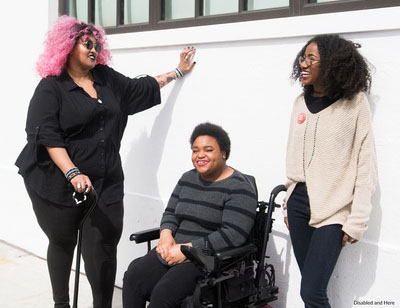 Three friends enjoying a conversation outdoors, one using a wheelchair.