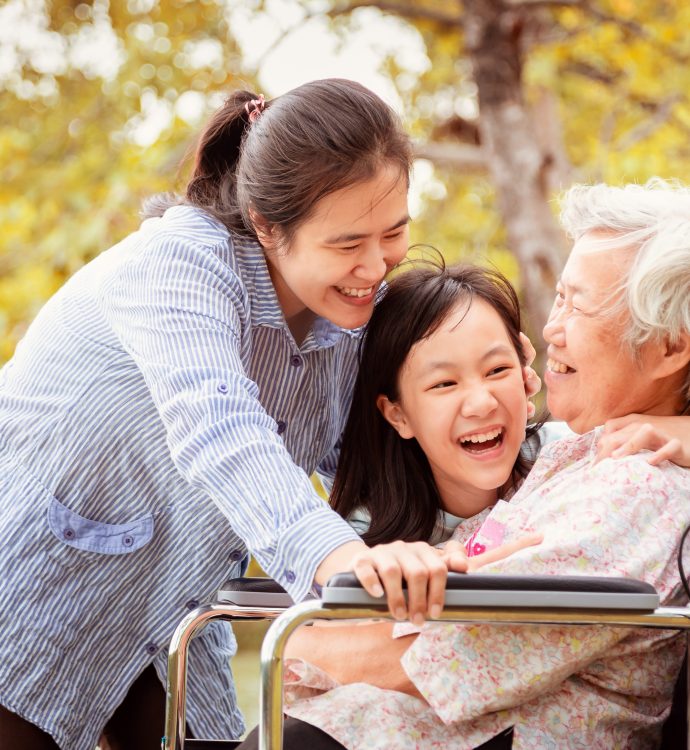 Happy family bonding with grandmother in wheelchair outdoors.