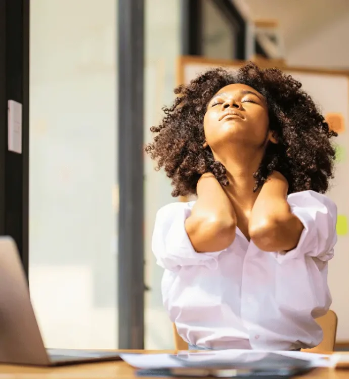A woman at her desk holding her neck in discomfort, illustrating back and musculoskeletal pain at work.