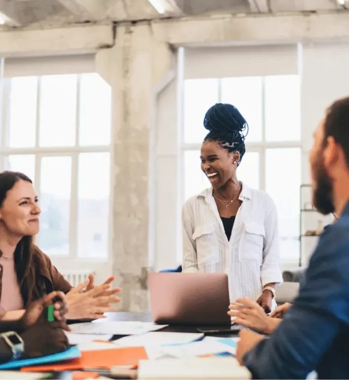 A diverse team smiling and collaborating in a bright modern office, representing LifeSpeak’s focus on workplace wellbeing and supportive leadership.
