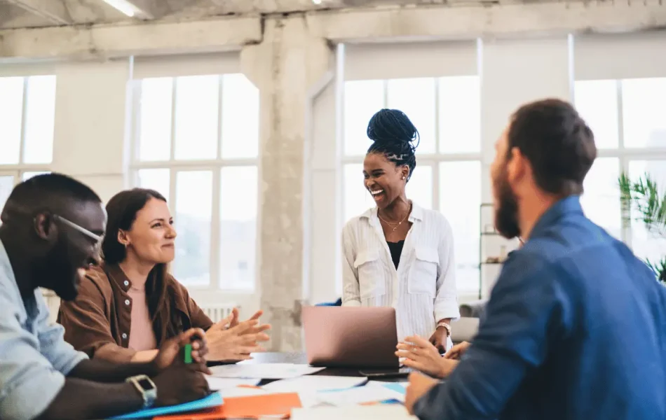 A diverse team smiling and collaborating in a bright modern office, representing LifeSpeak’s focus on workplace wellbeing and supportive leadership.