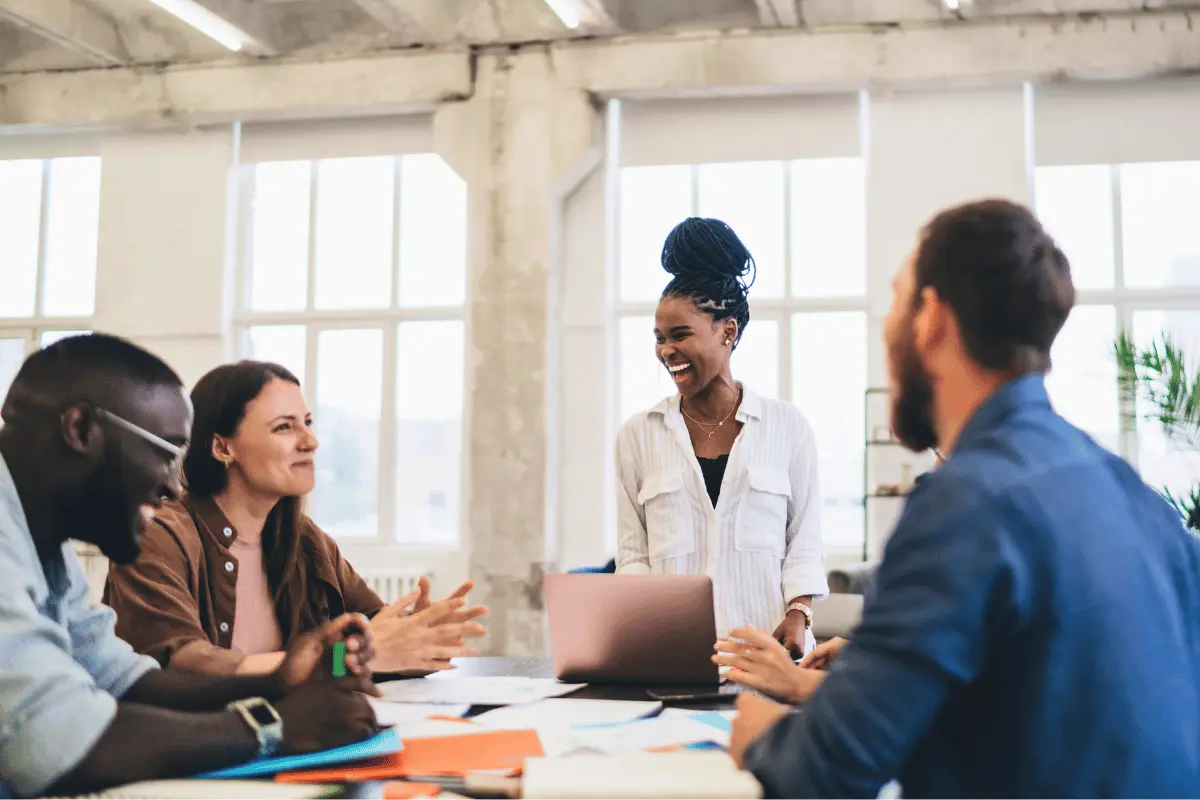 A diverse team smiling and collaborating in a bright modern office, representing LifeSpeak’s focus on workplace wellbeing and supportive leadership.