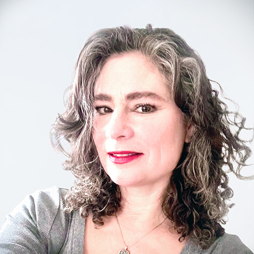 Smiling woman with curly hair in a gray top.