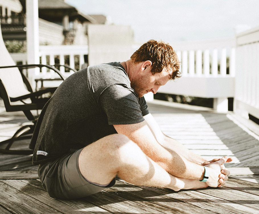Man stretching on a sunny deck, fitness and relaxation in a tranquil outdoor setting.