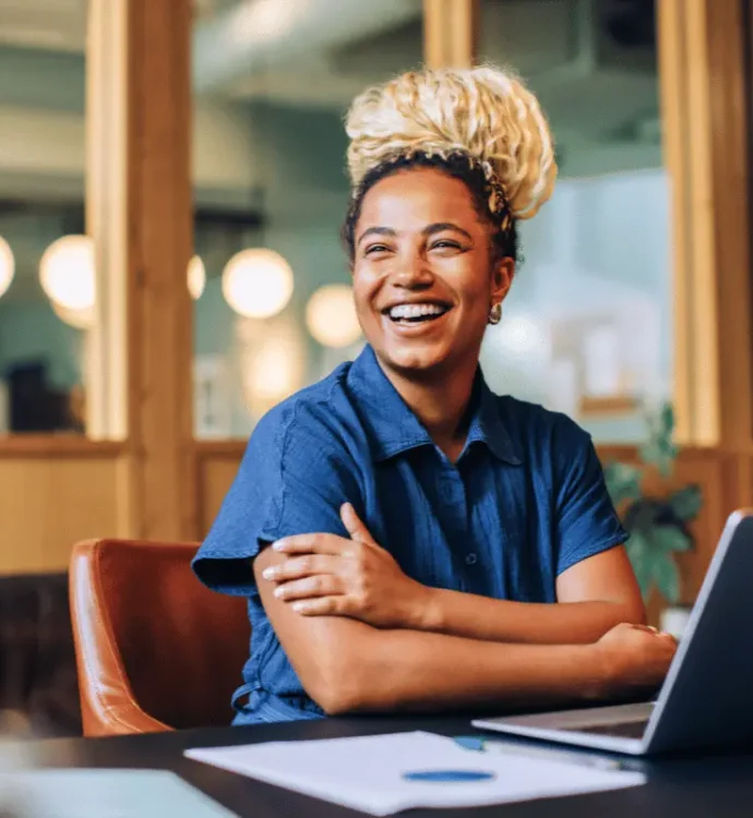 HR leader smiling while reviewing open enrollment communication materials on a laptop in a modern office.