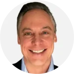Smiling man in a suit with a light background, headshot/portrait.