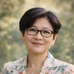 Person in glasses smiling outdoors in floral blazer.