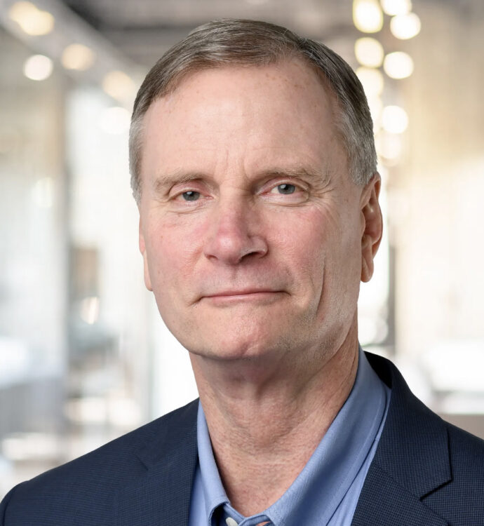 Professional middle-aged man in business attire, serious expression, office background.